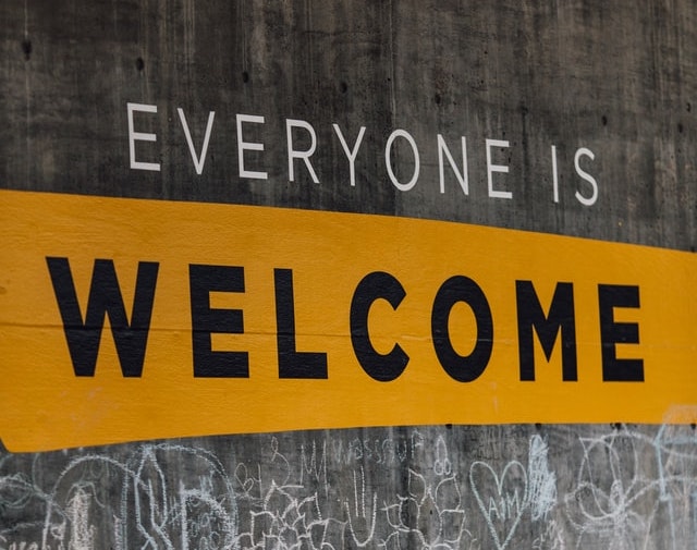 A sign painted on a concrete wall reads 'everyone is welcome'