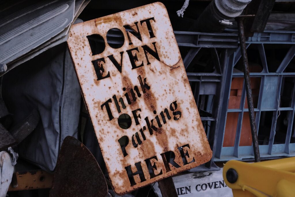 A rusty sign reads 'don't even think of parking here'