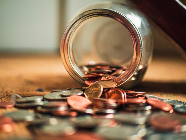 a glass jar on it's side with pennies spilling out