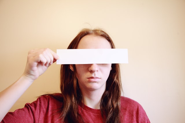 Someone holding a blank rectangle in front of their face, covering their eyes