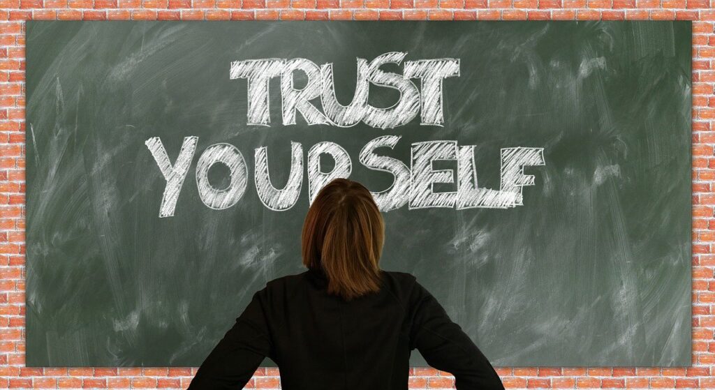 Woman facing a chalkboard which reads Trust Yourself