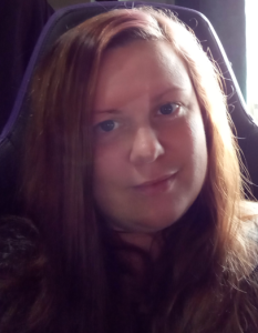 A white woman with long auburn red hair and blue eyes.
